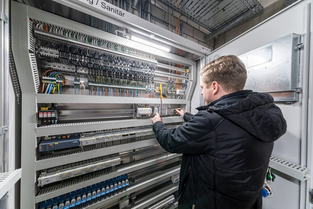 Projektleiter der Hälg & Co. AG Gebäudeautomation vor einem Schaltschrank.