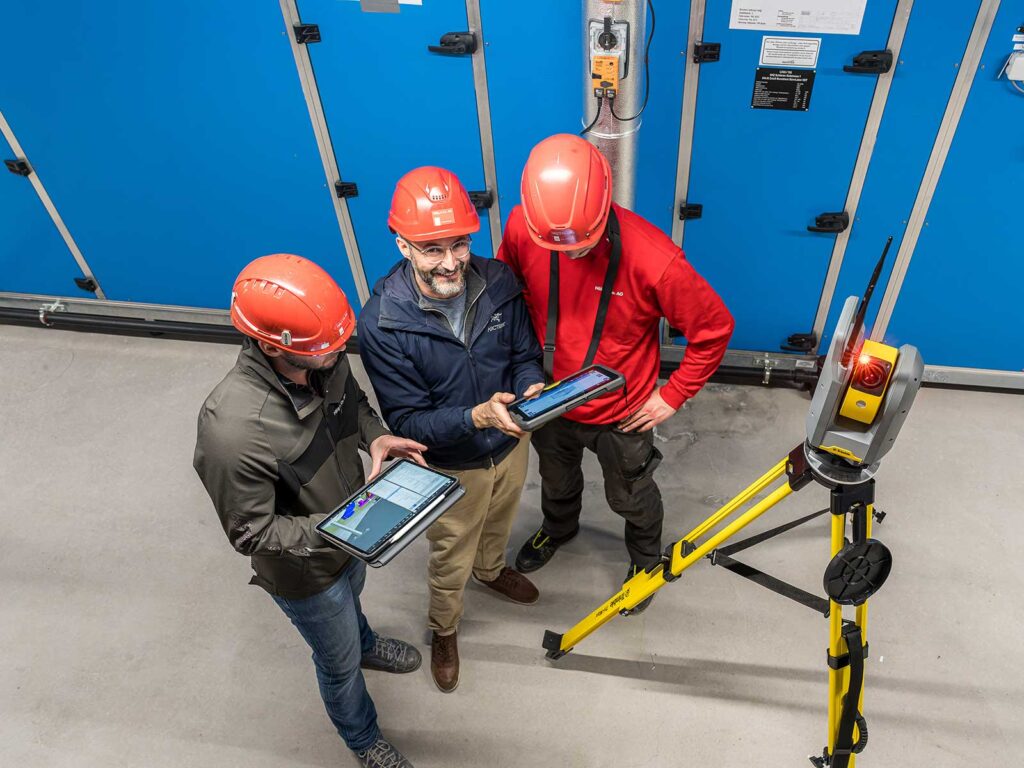 Digital auf der Baustelle: Drei Mitarbeitende der Hälg Group mit Tablets.