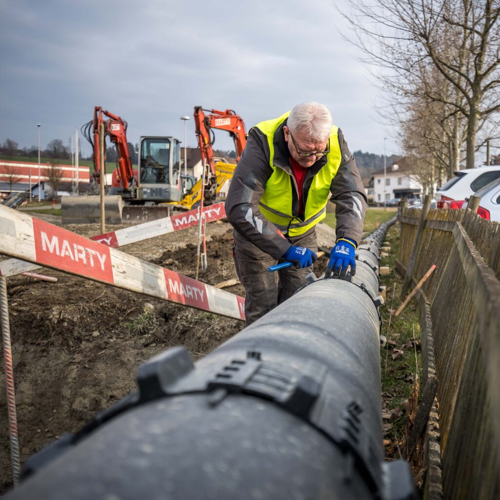 Un collaborateur de Hälg & Cie travaille sur une conduite dans le cadre d'un projet de chaleur à distance.