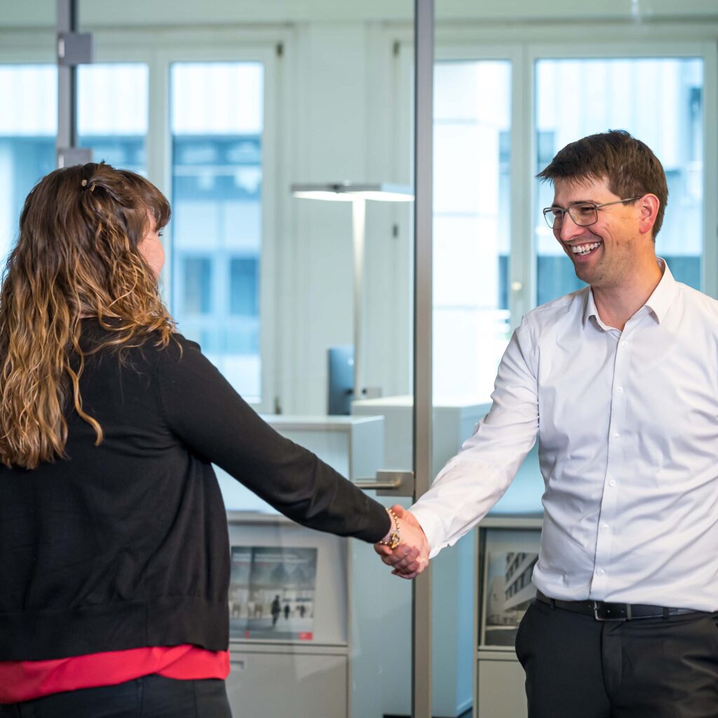 Handshake zwischen einer Kundin der Hälg Group und einem Mitarbeitendem der Hälg Group.