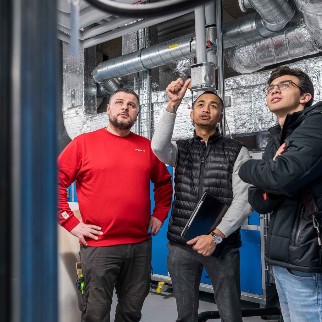 Drei Mitarbeitende der Hälg & Co. AG Aarau betrachten die Arbeit in einer Technikzentrale.