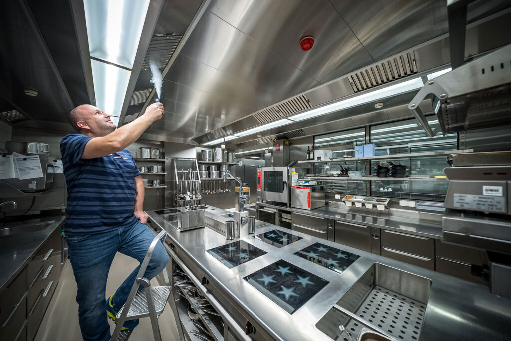 Der Lüftungsreiniger der Hälg & Co. AG prüft die reinigt die Lüftung in einer Gastroküche.