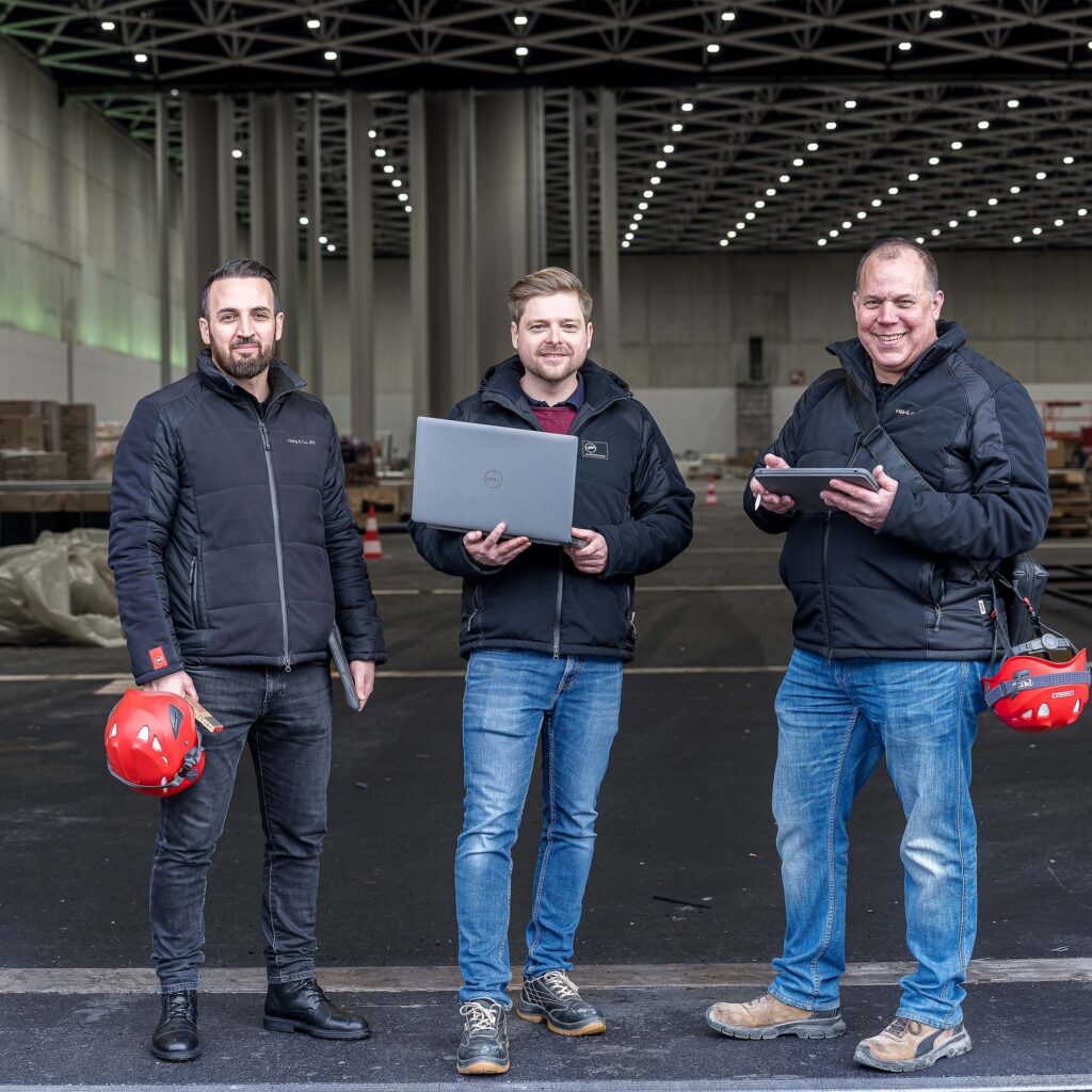 Drei Mitarbeitende vor der SGKB Halle in St. Gallen