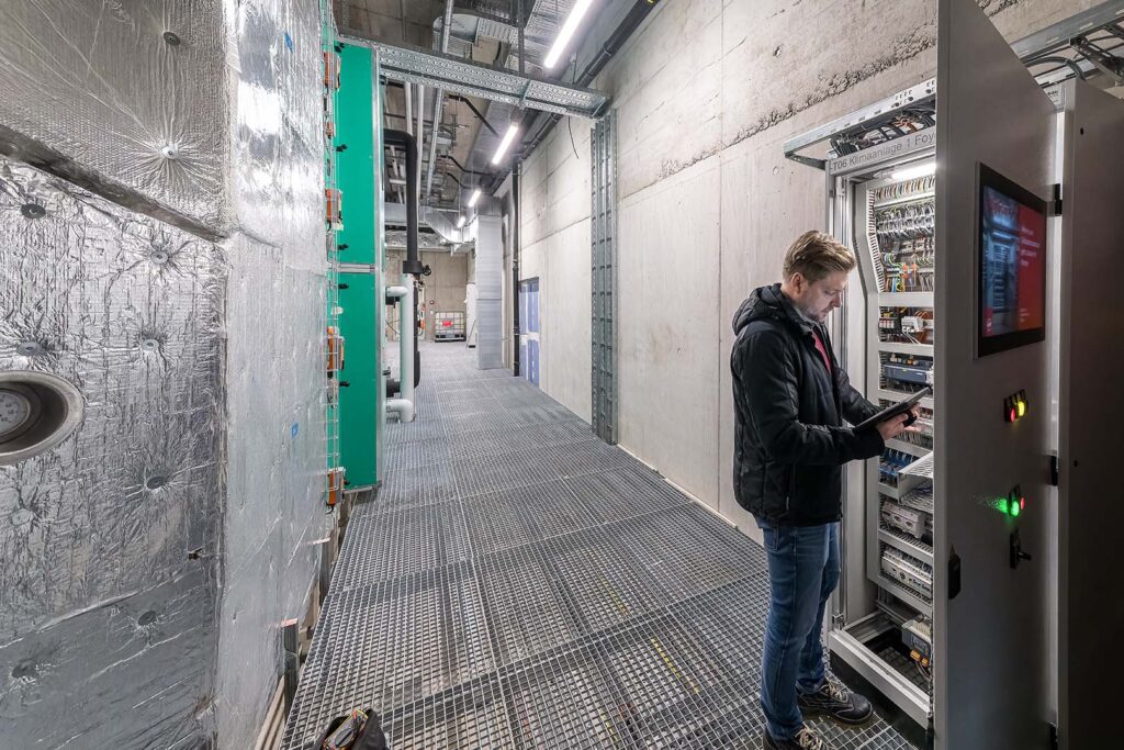 Mitarbeiter der Hälg & Co. AG Gebäudeautomation steht am Schaltschrank für die HLKS-Anlagen der SGKB Halle in St. Gallen.