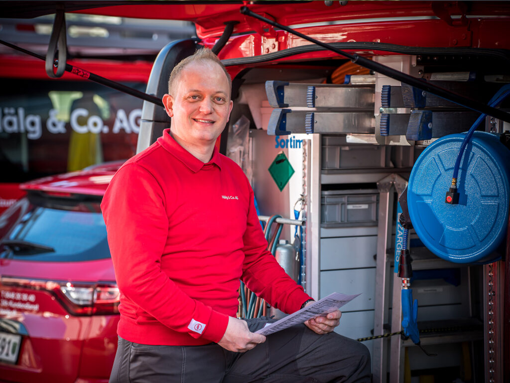 Technicien de service avec plan devant son véhicule.