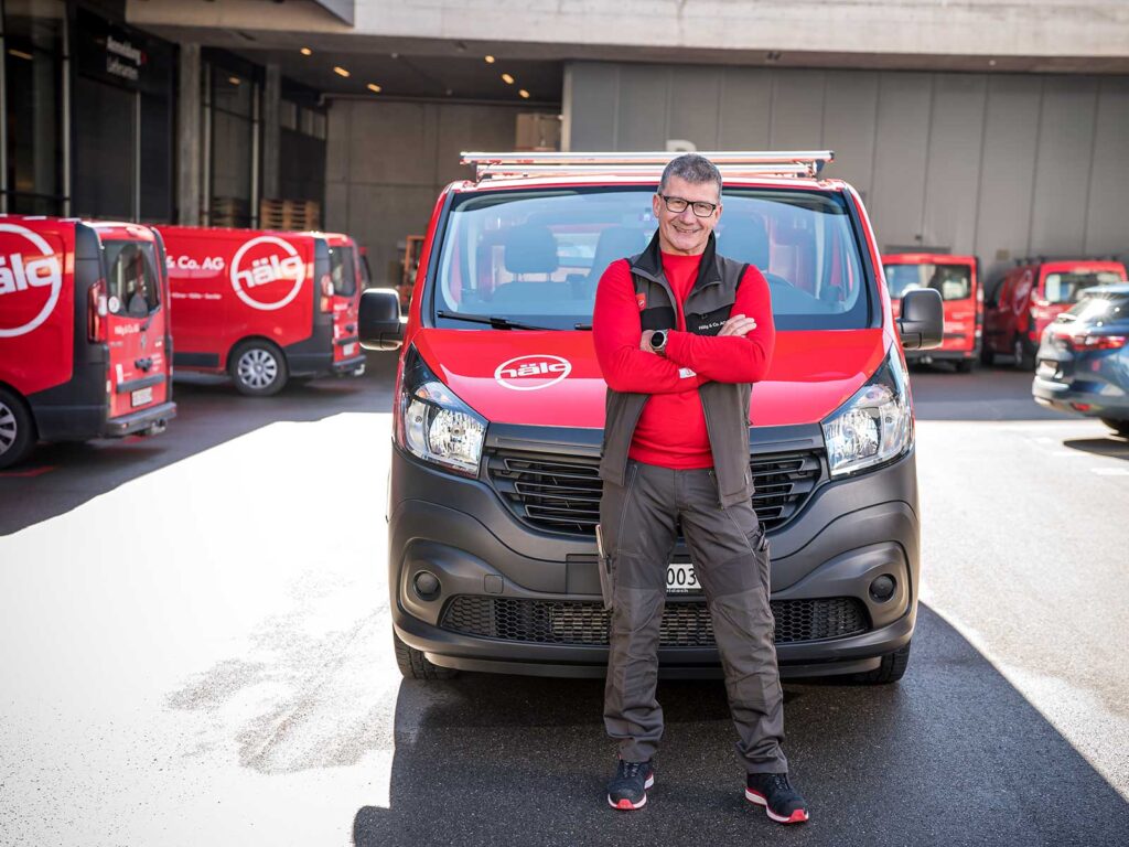 Un technicien de service de Hälg Group se tient devant sa voiture.