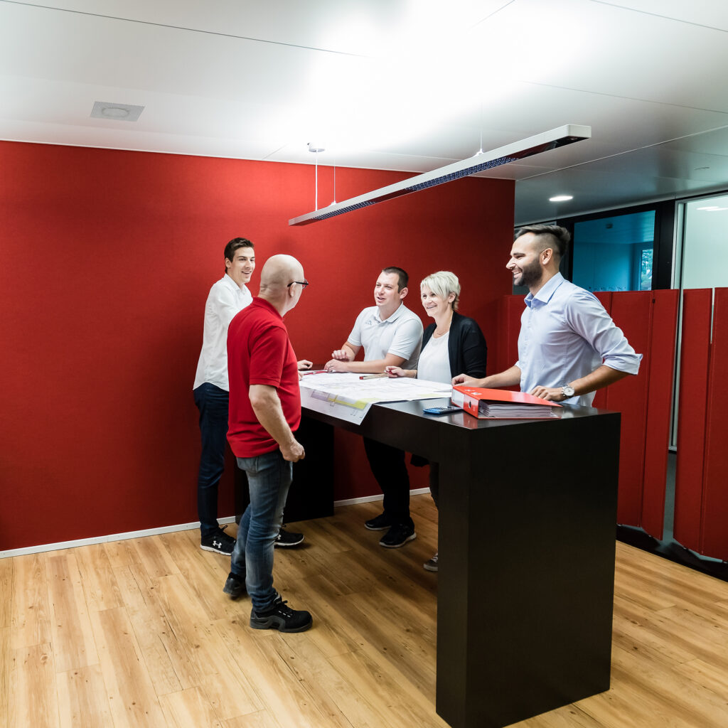 Des membres du personnel de Hälg Group sont debout autour d'une table.