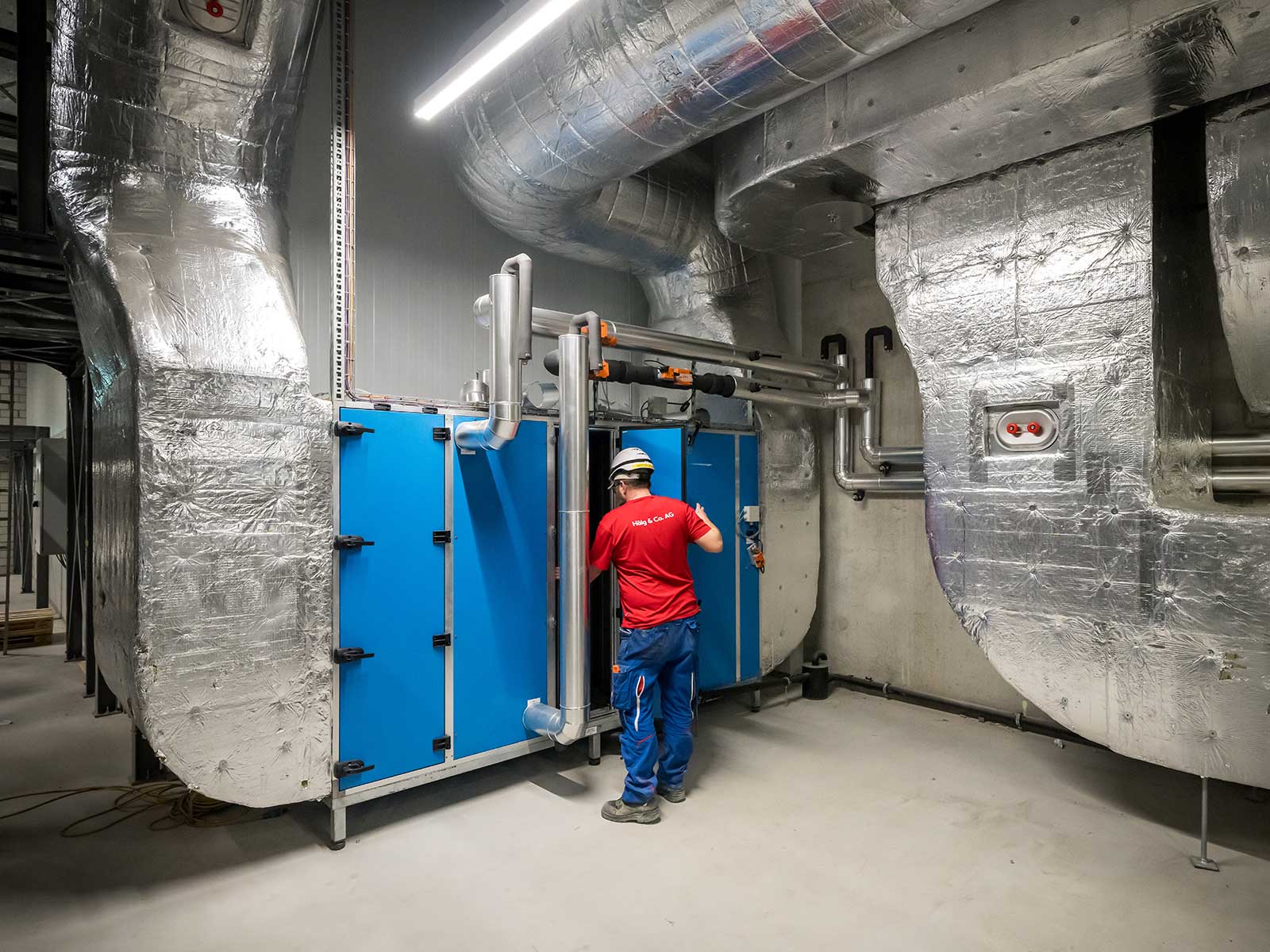 Ein Installateur der Hälg & Co. AG Bern steht vor eine Lüftungsanlage bei der Bell in Oensingen.