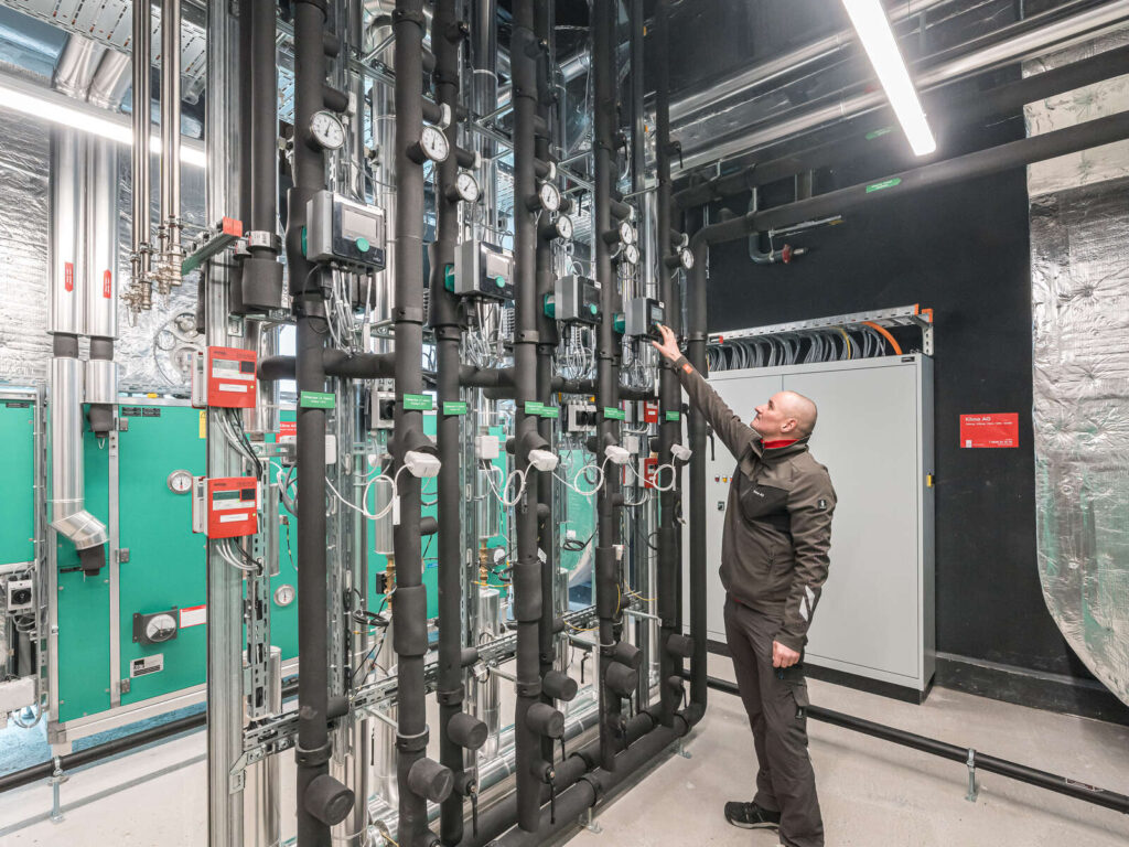 Mitarbeiter der Klima AG in Basel steht vor einer neu installierten Heizungsverteilung.