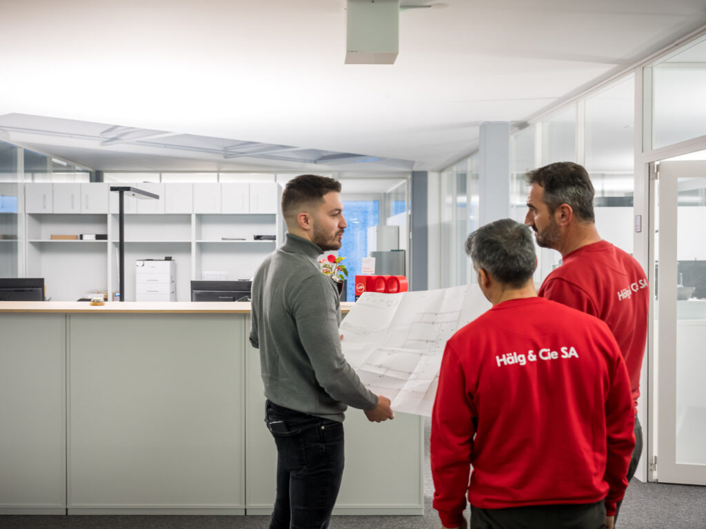 Drei Mitarbeitende der Hälg & Co. AG Fribourg blicken auf einen Plan.