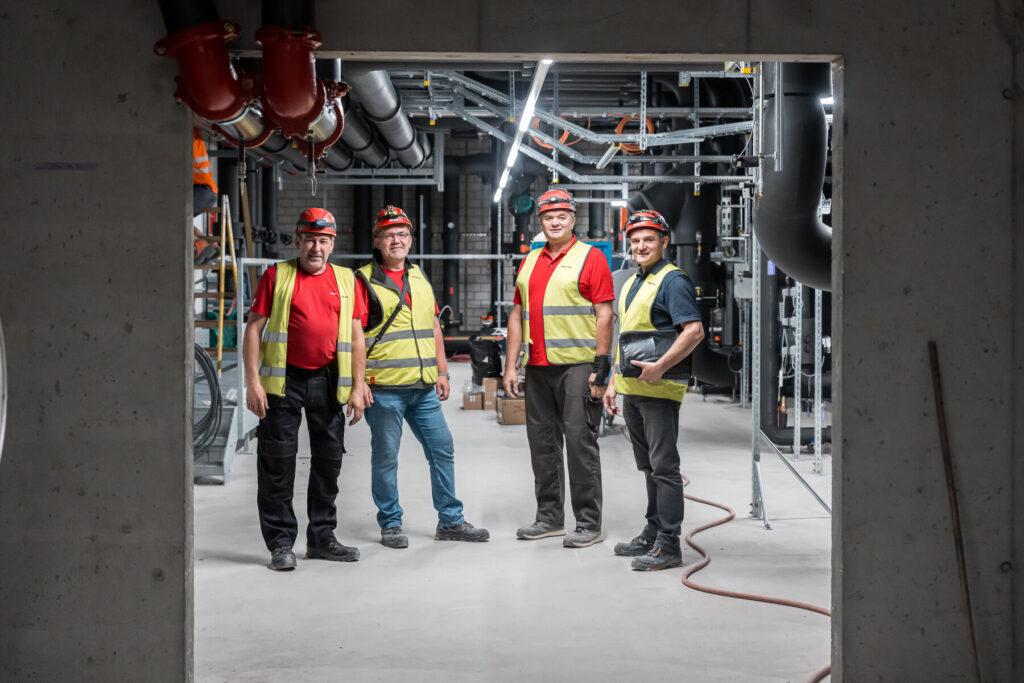 Vier Mitarbeitende der Hälg & Co. AG Aarau auf der Baustelle des Kantonsspitals Aarau und blicken in die Kamera.