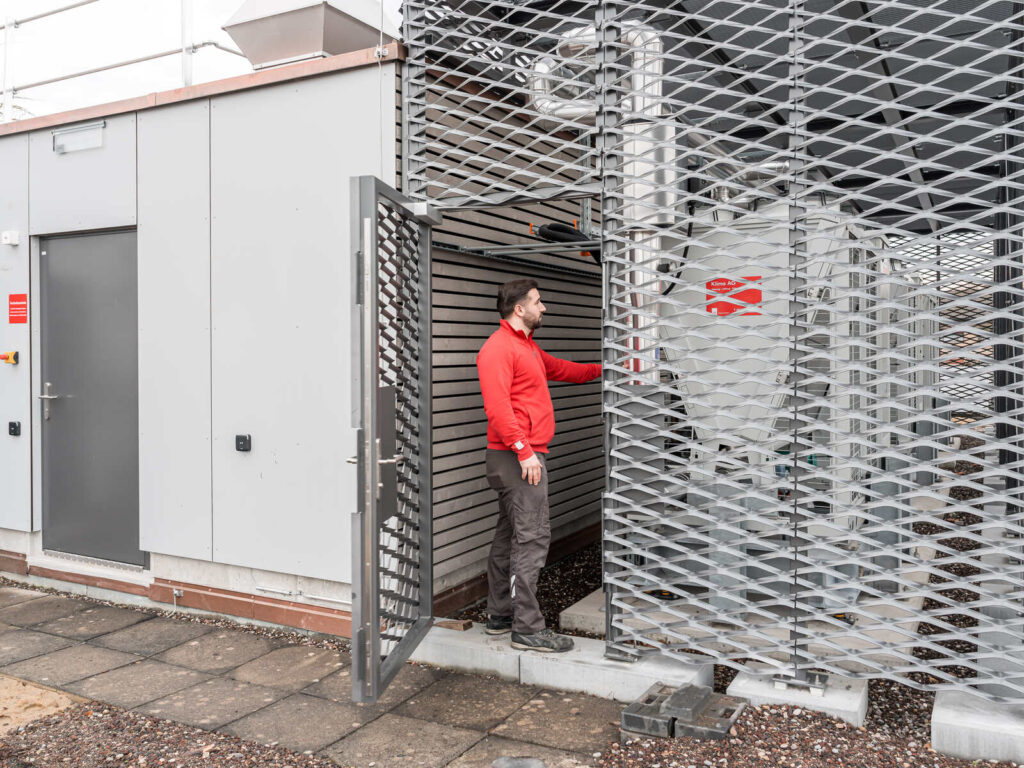 Ein Installateur der Klima AG Basel steht vor eine gebäudetechnischen Anlage.