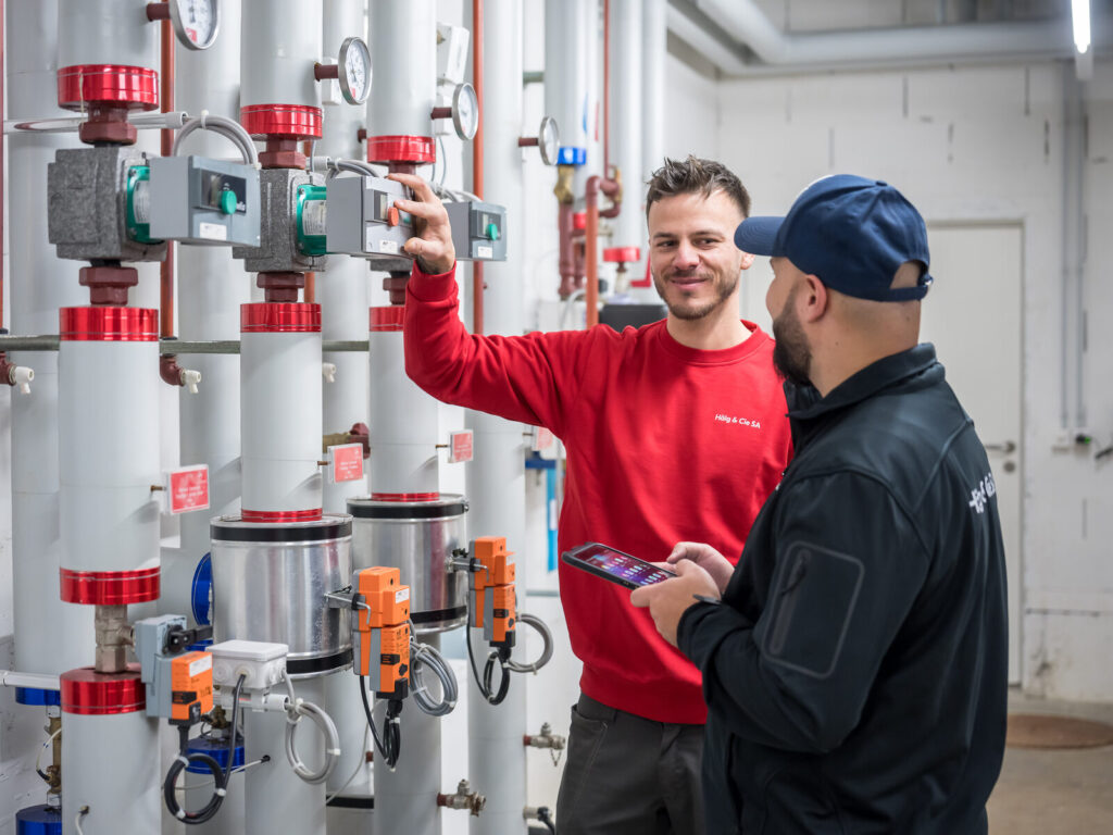 Zwei Mitarbeitende der Hälg & Co. AG Fribourg prüfen eine Anlage.