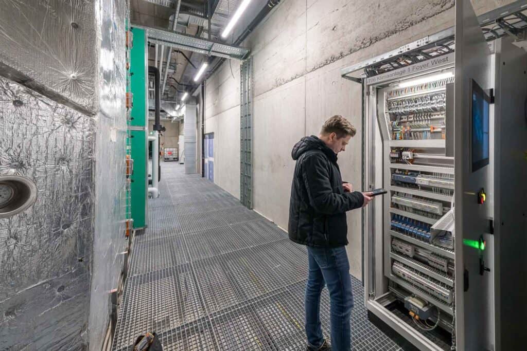 Techniker am Schaltschrank der Gebäudeautomation für die Lüftungsanlagen in der St. Galler Kantonalbank Halle